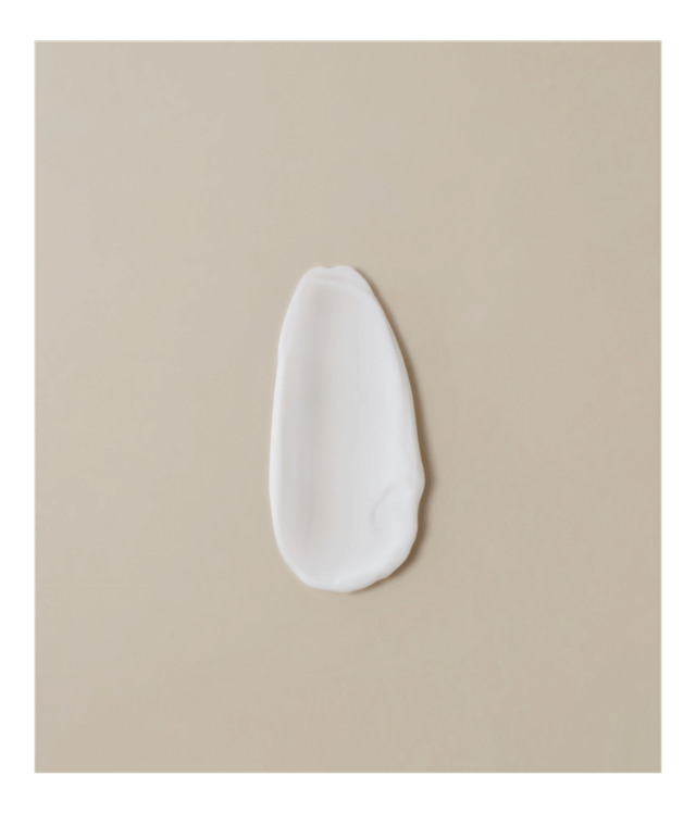 Porção de creme branco espalmado mostrando textura cremosa da loção