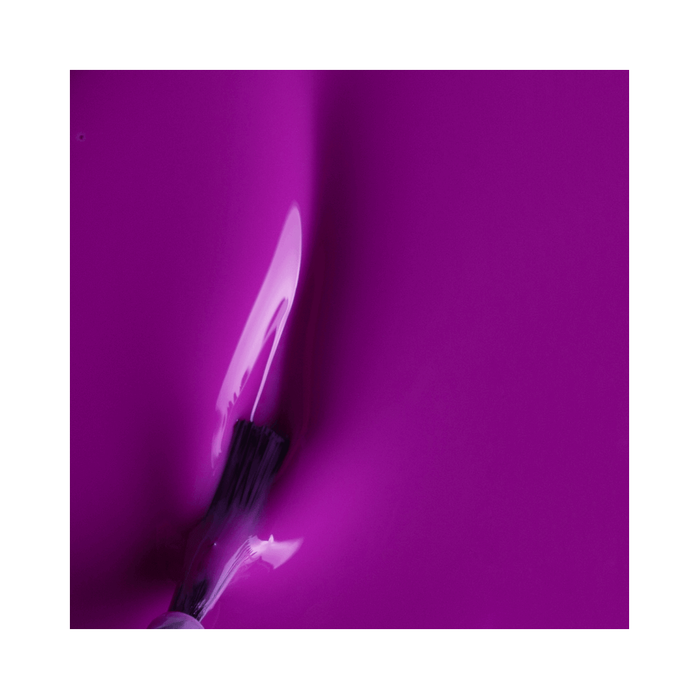 Close do pincel aplicando o esmalte roxo cremoso, mostrando textura e cobertura
