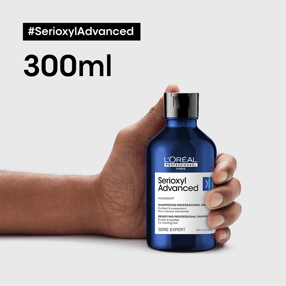 Mão segurando embalagem do shampoo Serioxyl Advanced 300ml destacando volume