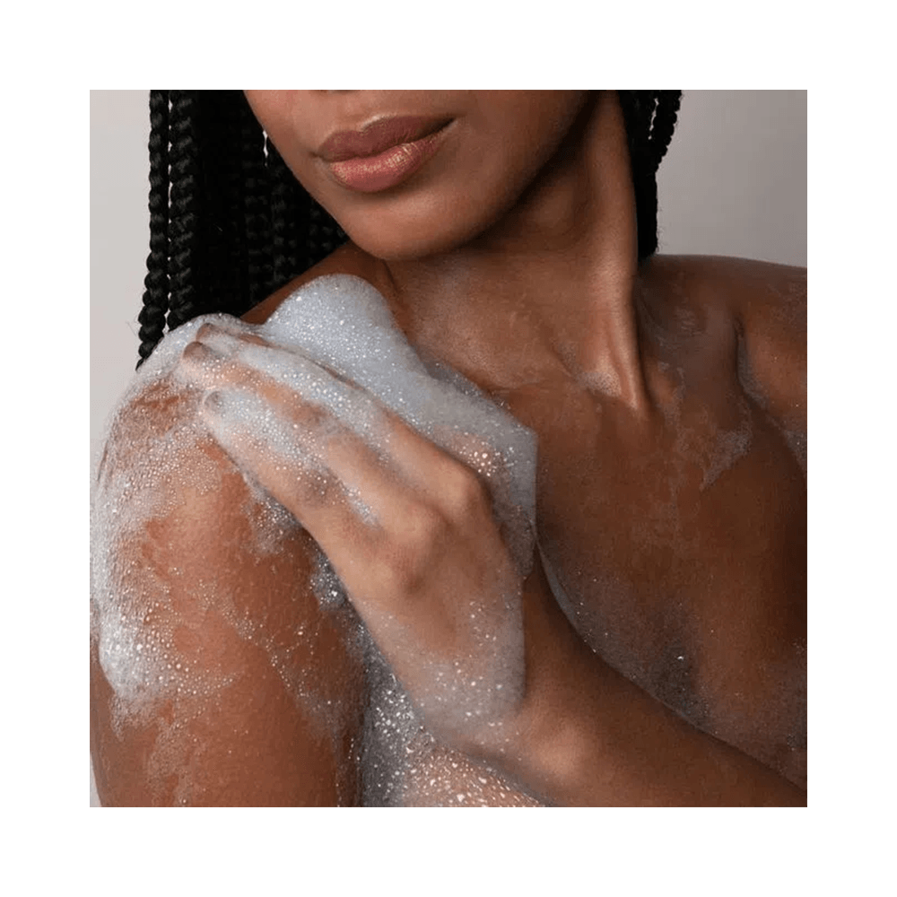 Mulher aplicando sabonete com espuma cremosa no corpo