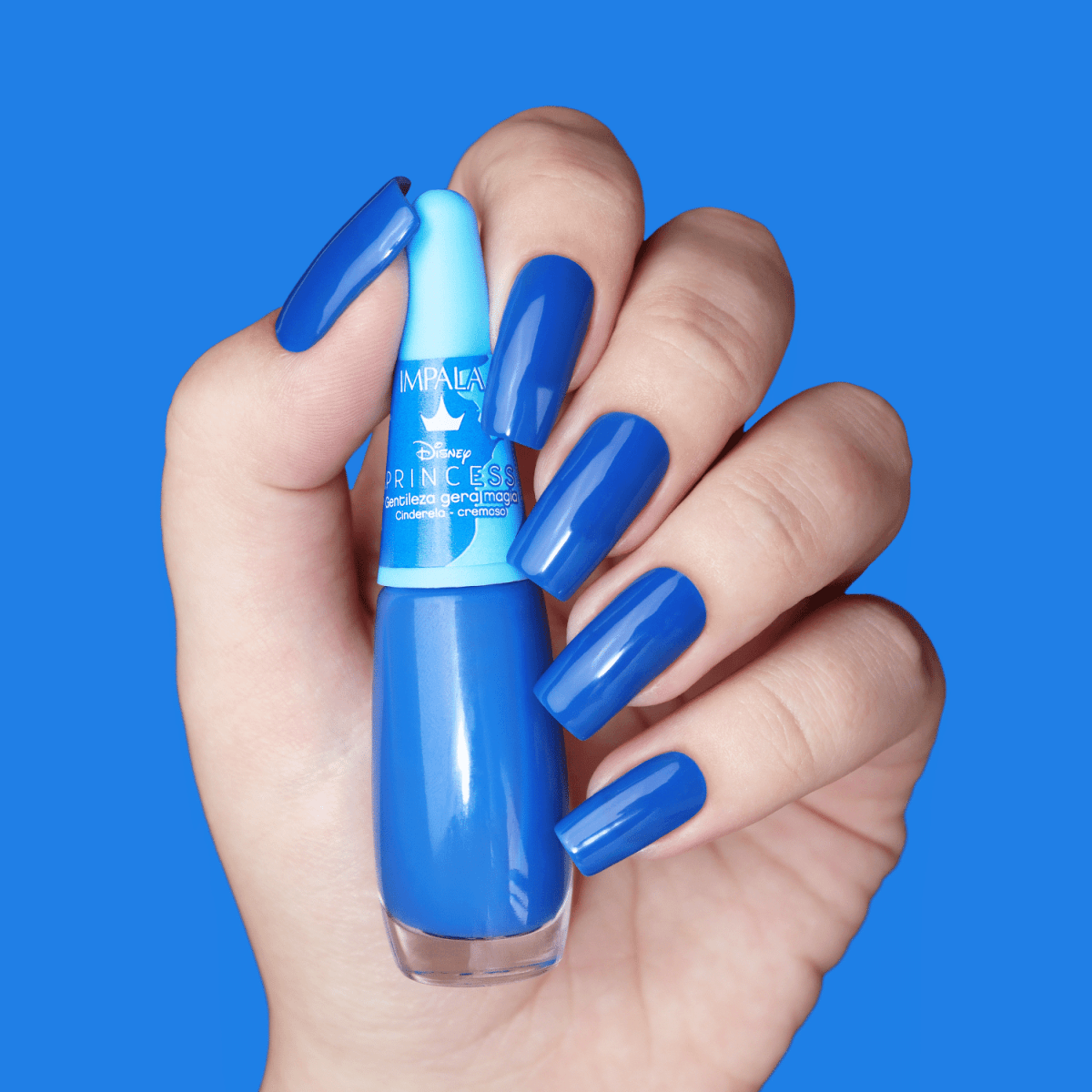 Mão com unhas pintadas segurando o esmalte Impala Disney Cinderela