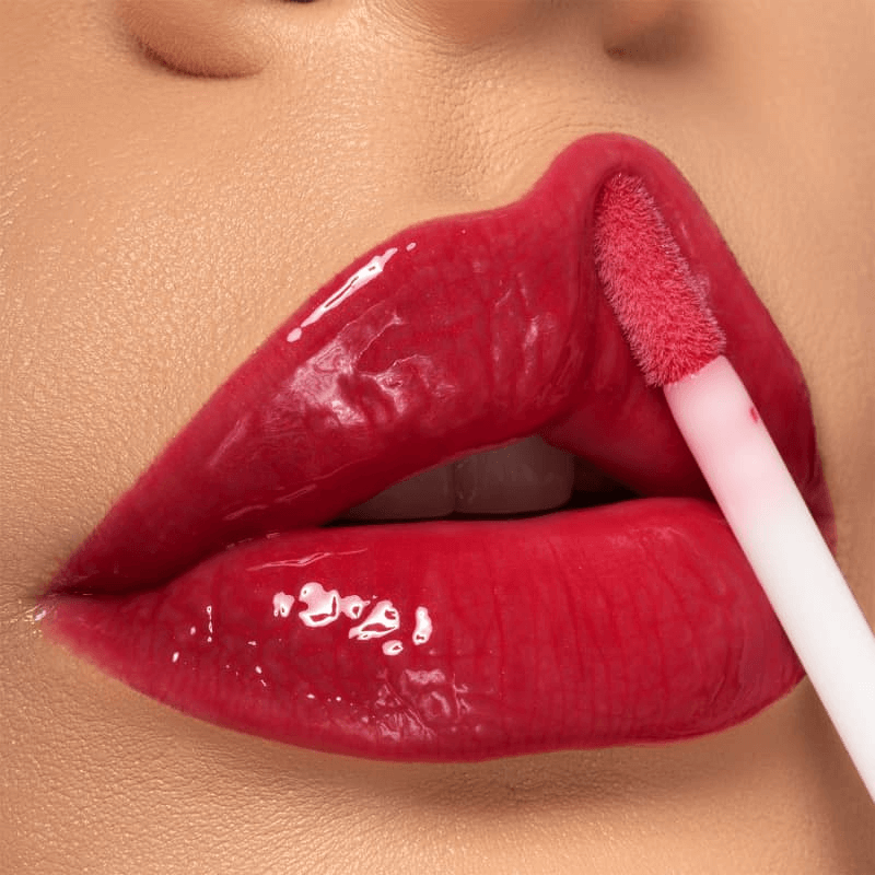 Aplicador de esponja aplicando gloss vermelho rubi, textura leve e não pegajosa