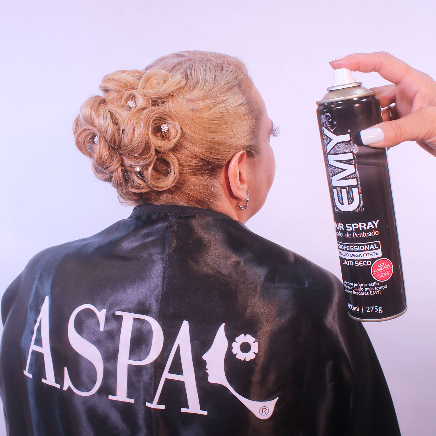 Produto em uso - profissional finalizando penteado com spray EMY