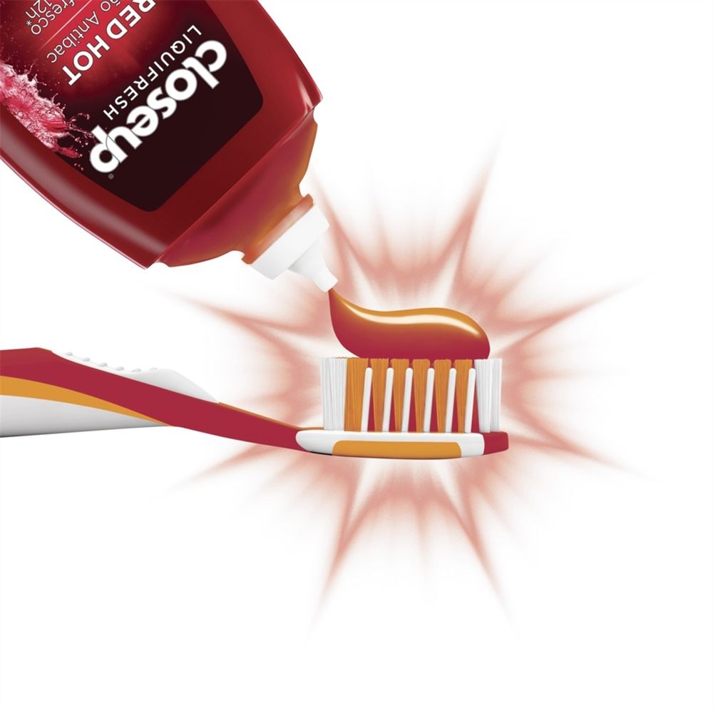 Aplicação do gel vermelho na escova de dentes mostrando textura e facilidade de uso