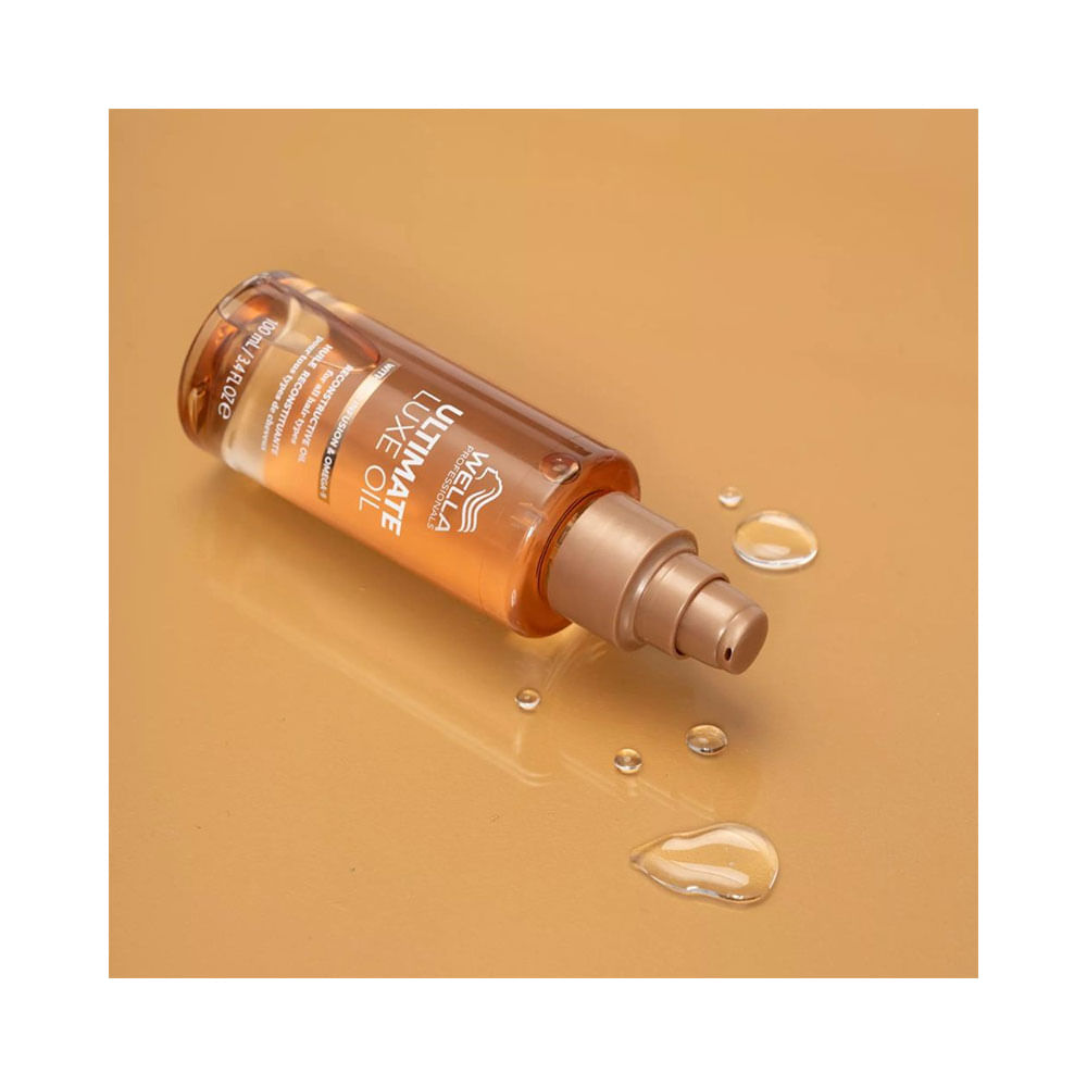 Frasco deitado do óleo Wella Ultimate Luxe Oil com gotas do produto