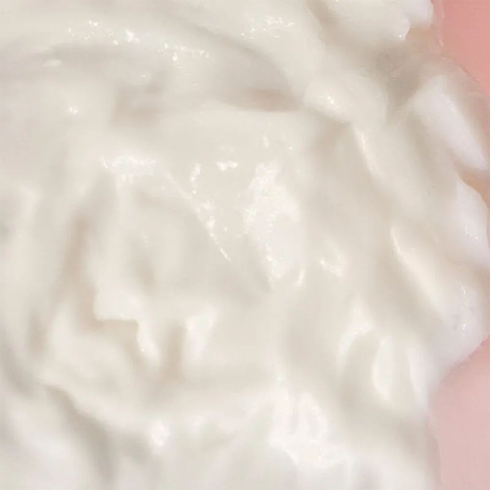 Close da textura cremosa branca do Leave-in Braé Hair Protein, evidenciando consistência nutritiva