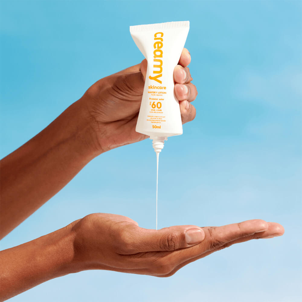 Mãos aplicando o protetor Creamy mostrando textura líquida e fluida