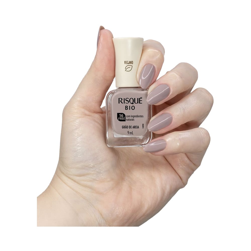 Mão segurando frasco do esmalte Risqué Bio Grão De Areia com unha pintada