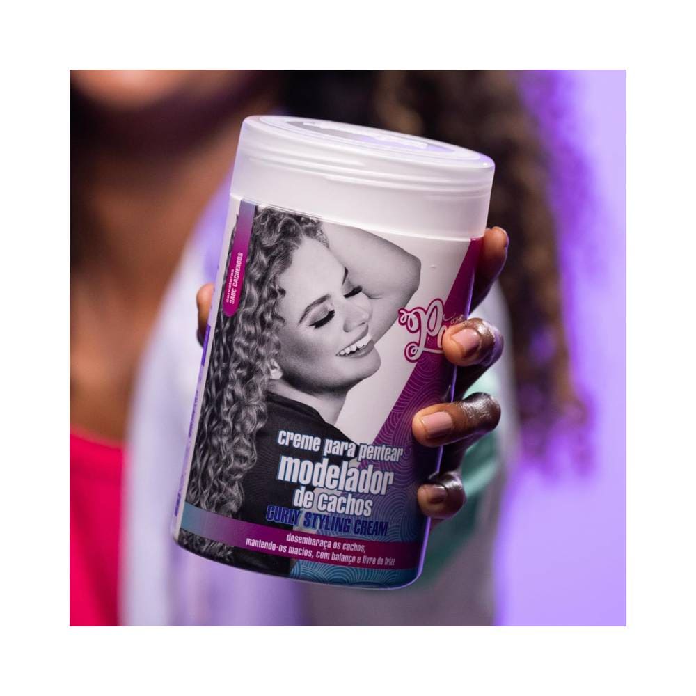 Mão segurando pote de Soul Power Curly Styling Cream 800g