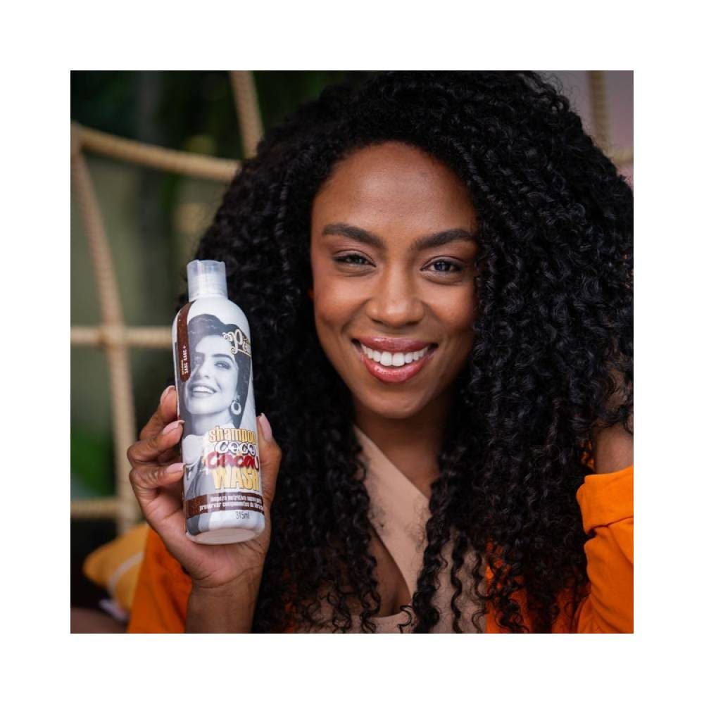 Mulher com cabelo cacheado segurando o Shampoo Soul Power Coco e Cacau Wash