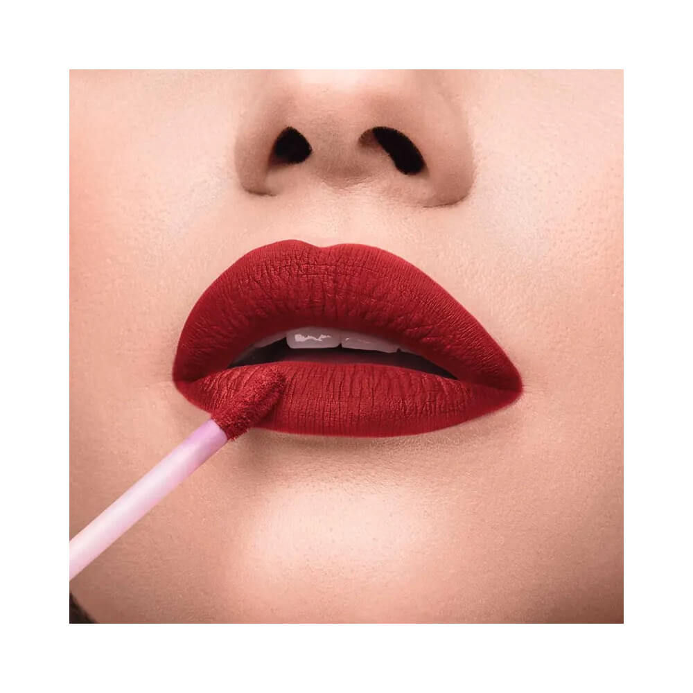 Close aplicador aplicando batom vermelho hibisco com acabamento matte