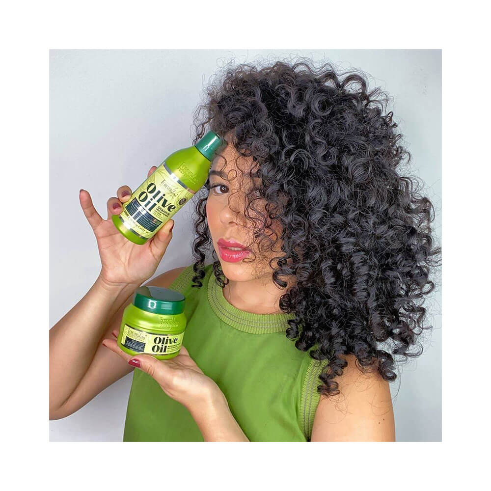 Mulher com cabelo cacheado segurando frasco de shampoo Forever Liss Olive Oil