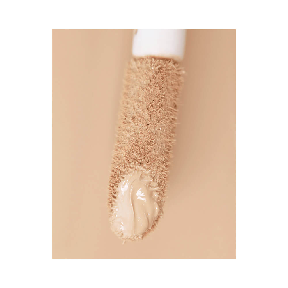 Close do aplicador com textura cremosa do corretivo Bruna Tavares