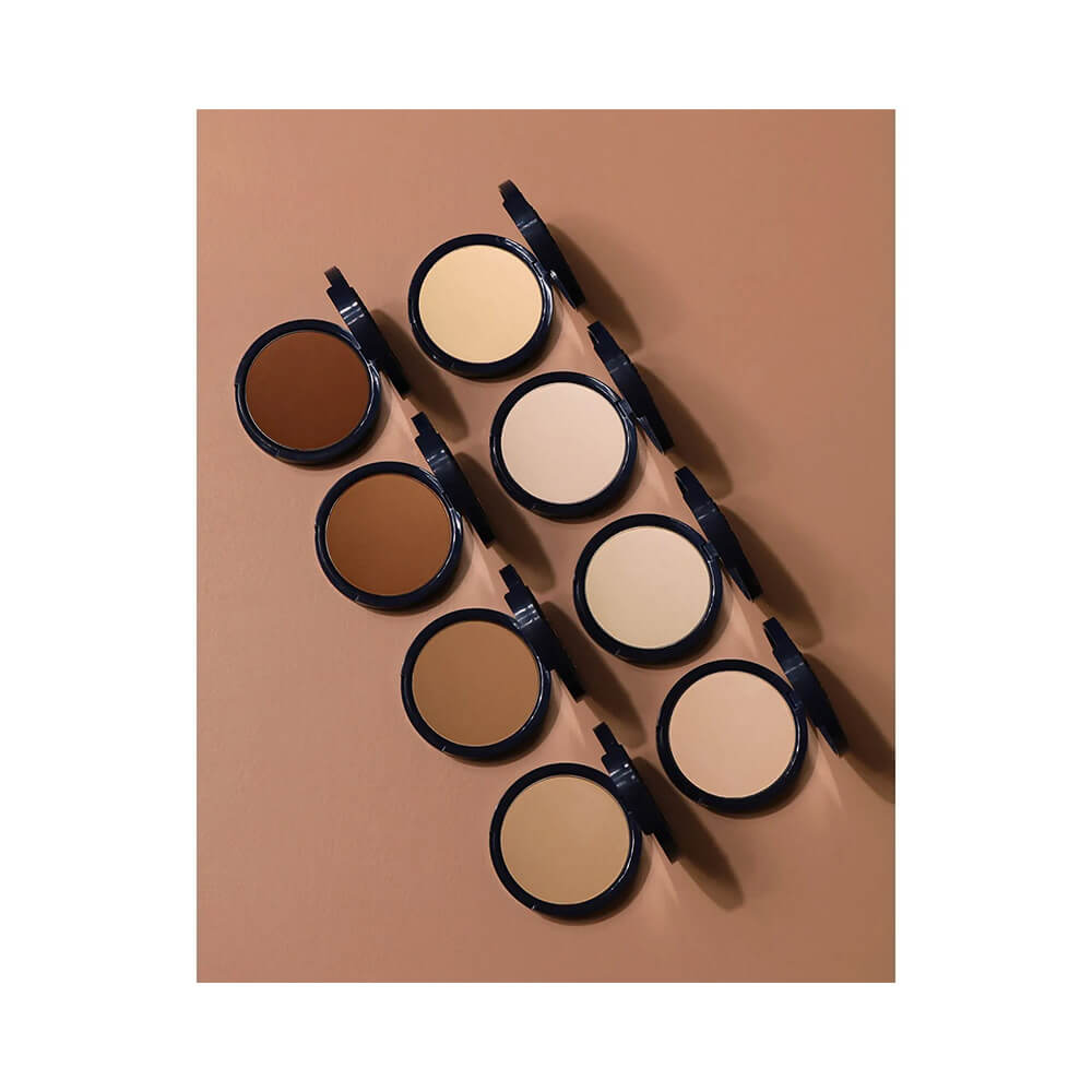 Diversos tons do Pó Compacto Bruna Tavares Powder 50 em embalagens azuis escuras abertas mostrando variações de cor