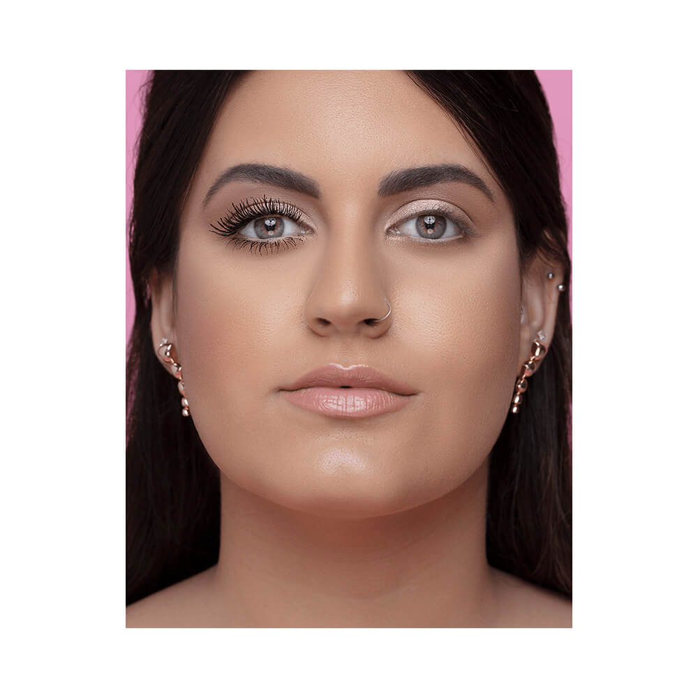 Rosto feminino com metade dos cílios superiores aplicados com Máscara de Cílios Bruna Tavares Biglash evidenciando volume e alongamento.