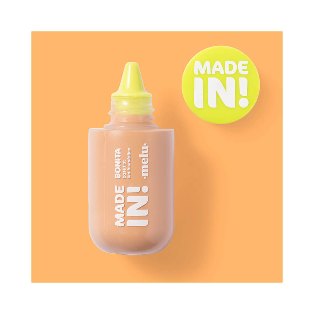Frasco da base líquida Melu Made In! Foundation Tint com tampa amarela removida mostrando design arredondado.