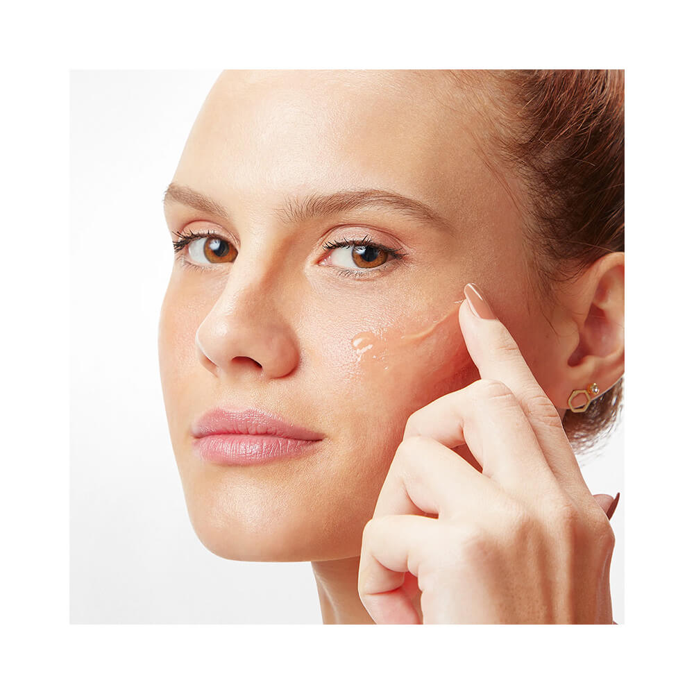 Mulher aplicando o Sérum Facial Beyoung Booster no rosto, mostrando textura leve e translúcida.