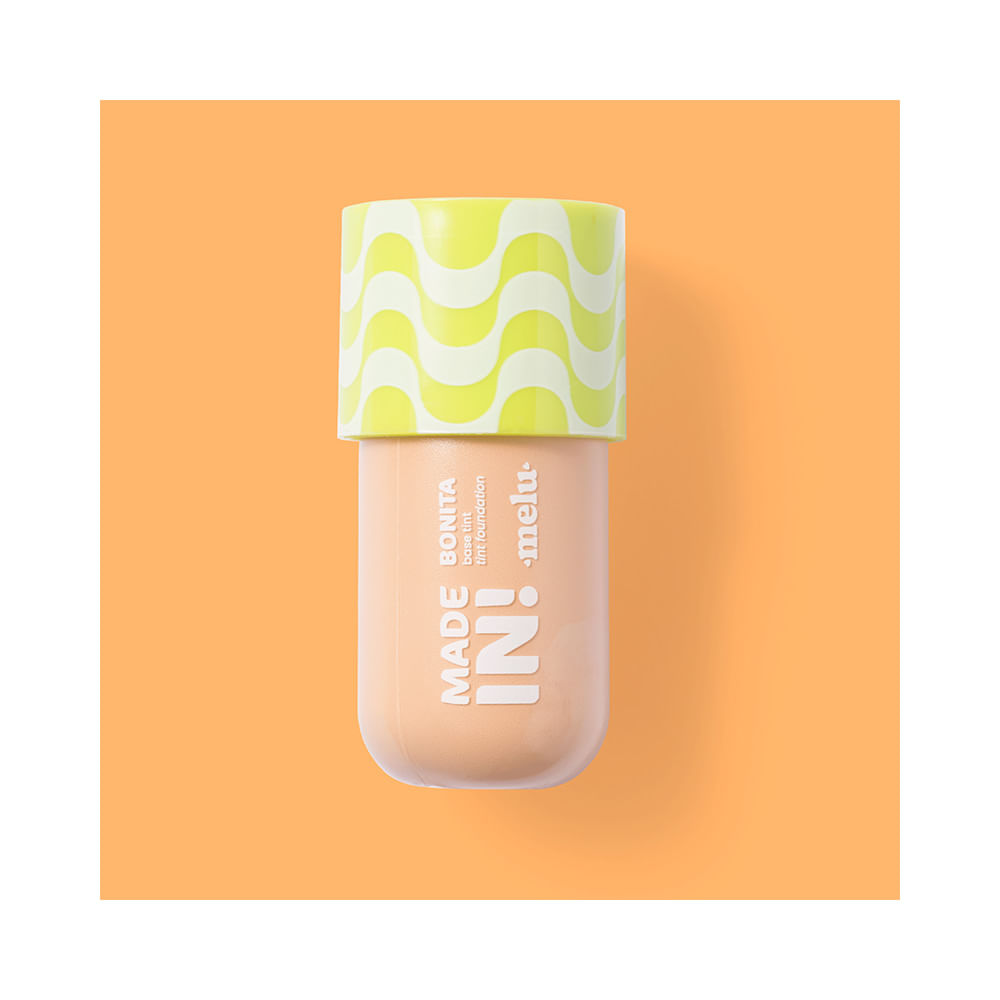 Detalhe do frasco Melu Foundation Tint 50 contra fundo laranja