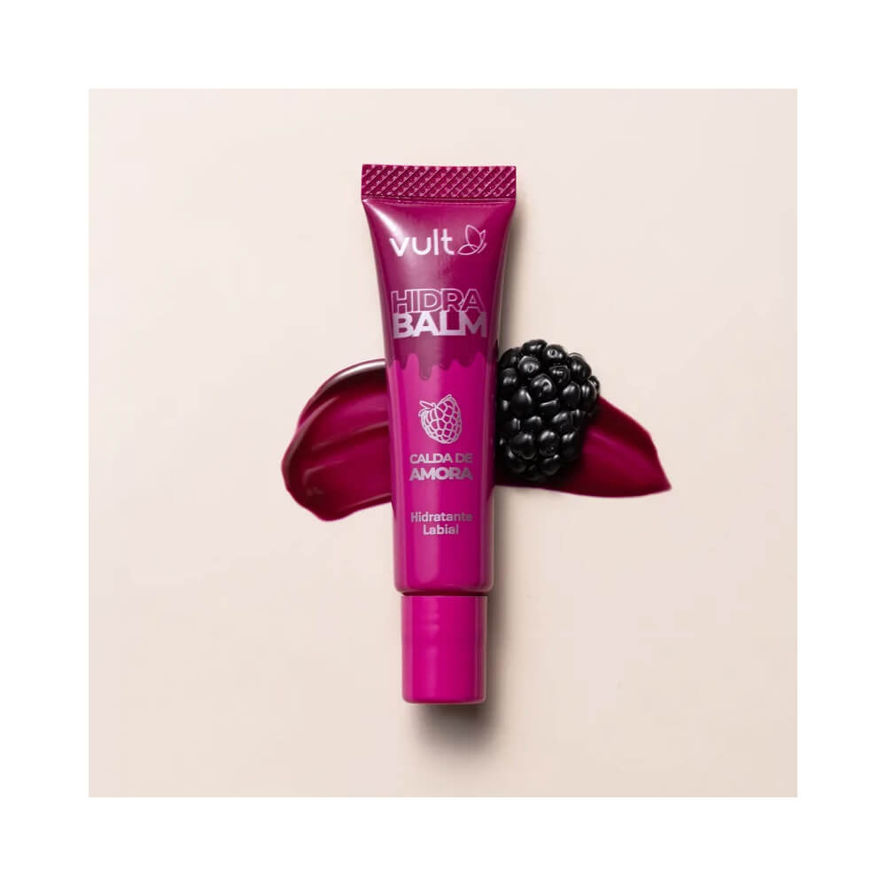 Tubo de hidratante labial Vult Hidra Balm Calda de Amora ao lado de uma amora sobre fundo bege