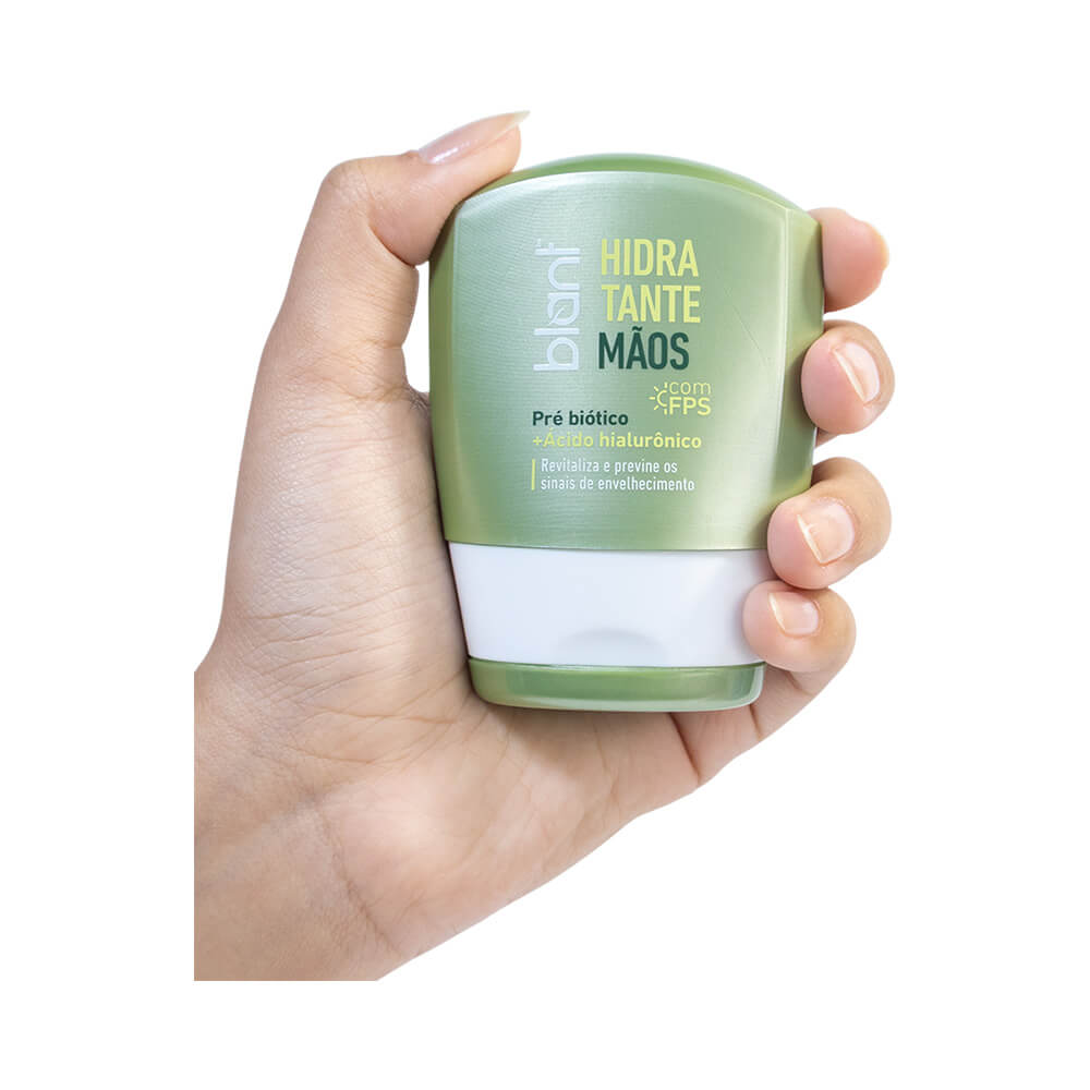 Mão segurando o hidratante Blant para mãos em tubo verde claro com tampa branca