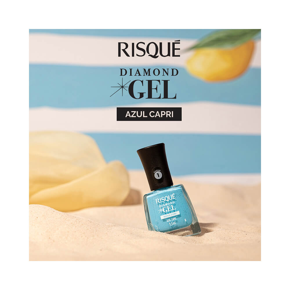 Esmalte Risqué Diamond Gel Azul Capri sobre areia com fundo listrado azul e branco