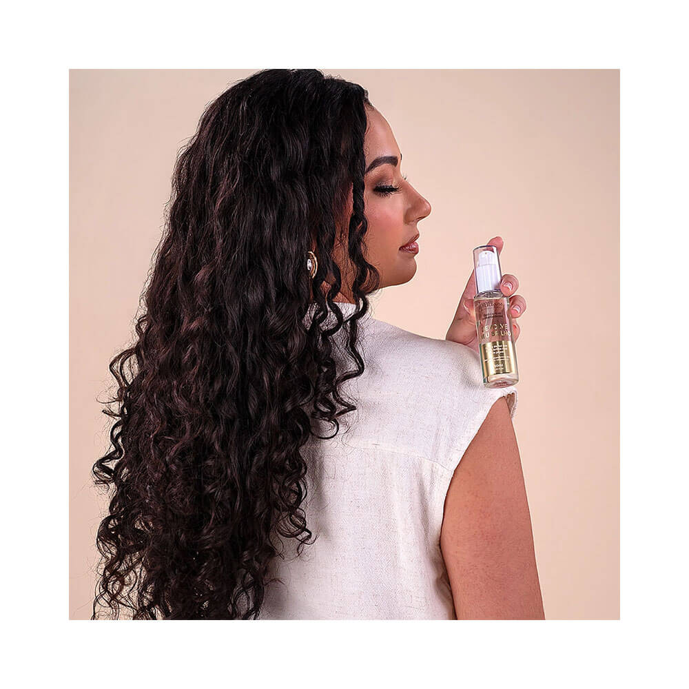 Mulher com cabelos cacheados segurando o óleo capilar Forever Liss 7ml