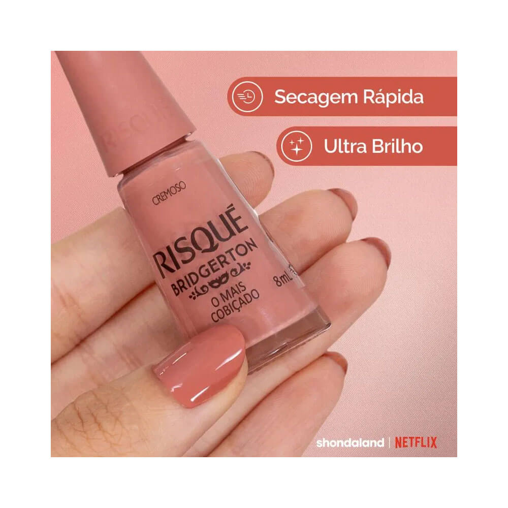 Esmalte Risqué Bridgerton O Mais Cobiçado com fundo rosa e mão segurando a garrafa