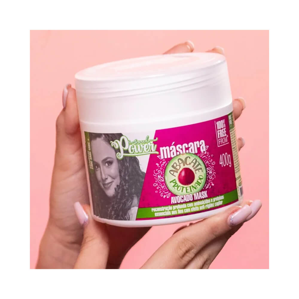 Mão segurando embalagem da Máscara Capilar Soul Power Abacate 400g com fundo rosa claro