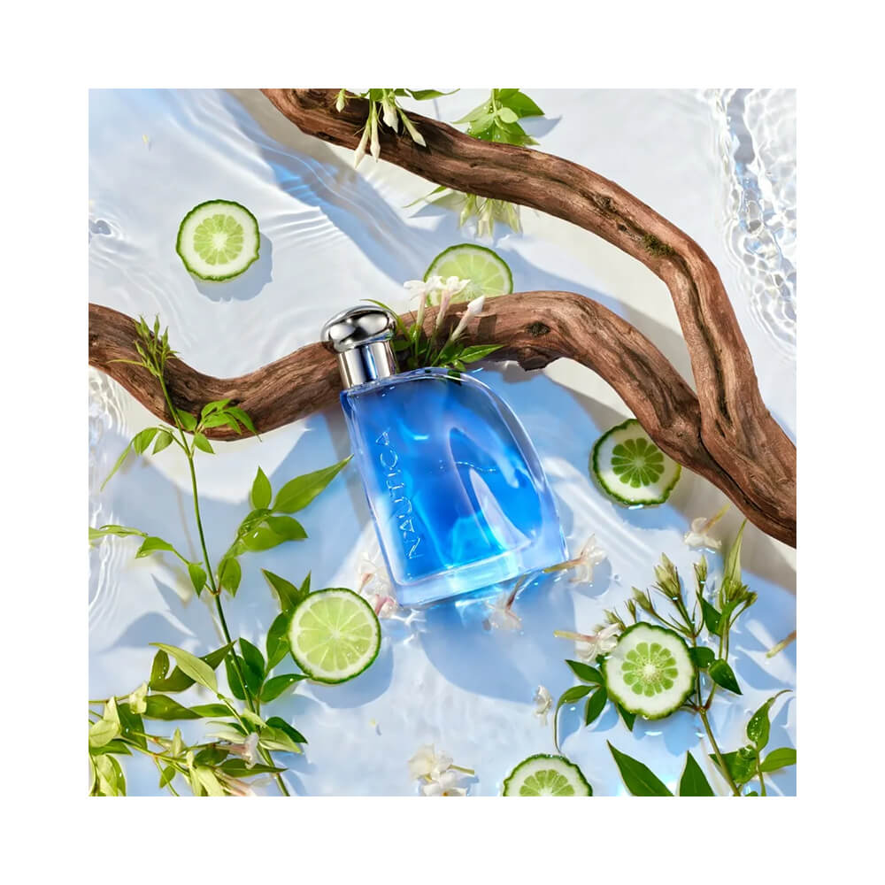 Frasco do perfume Nautica Blue sobre superfície branca com elementos naturais como água e madeira