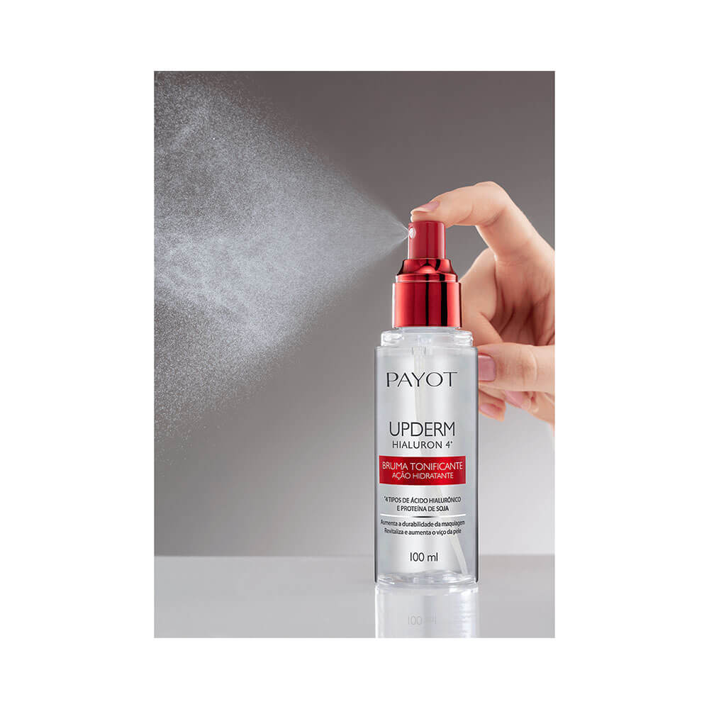 Mão aplicando a Bruma Tonificante Payot Upderm 100ml com spray liberando névoa fina