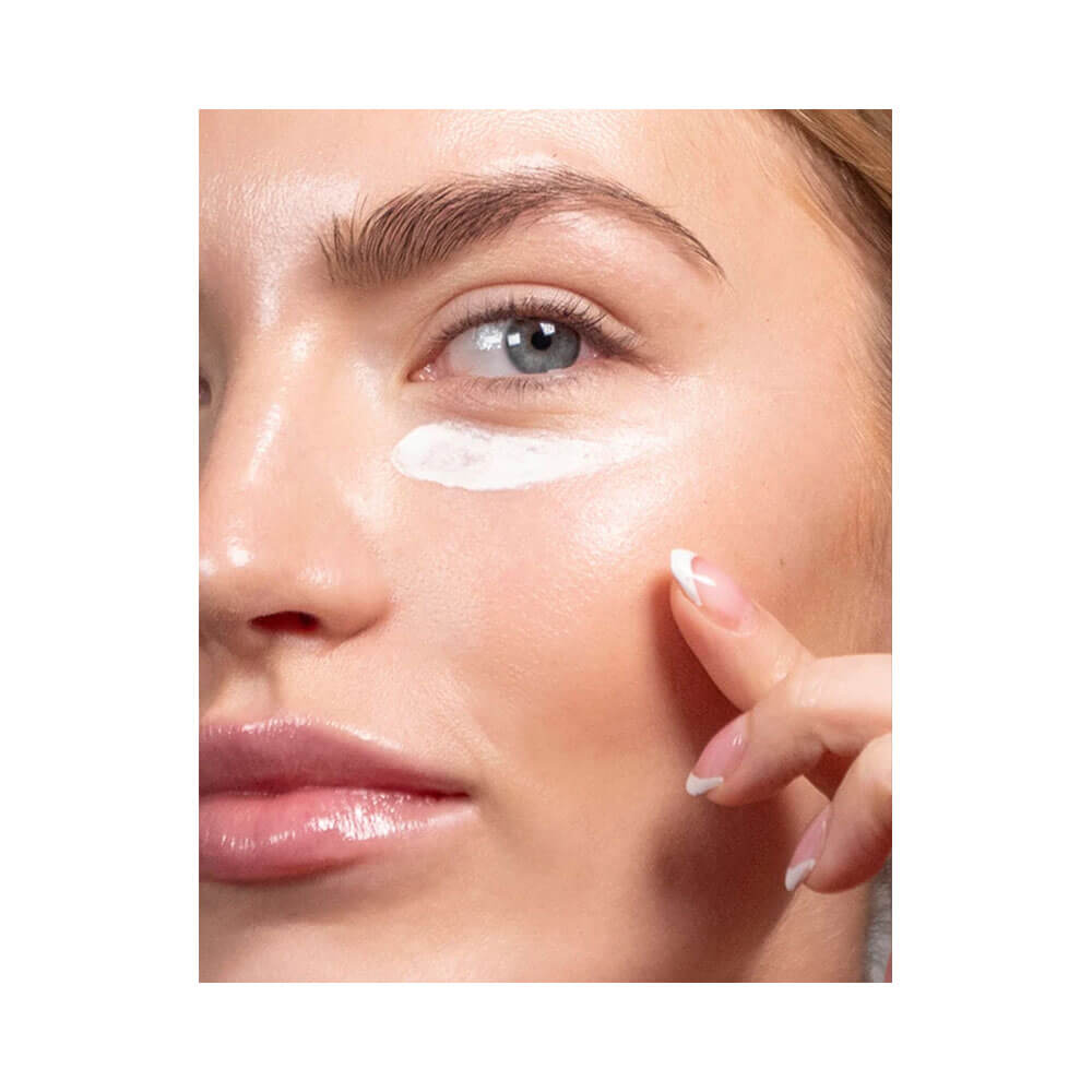 Mulher aplicando creme facial Korres Apothecary Wild Rose Clareador Noturno próximo ao olho, mostrando pele iluminada e saudável.