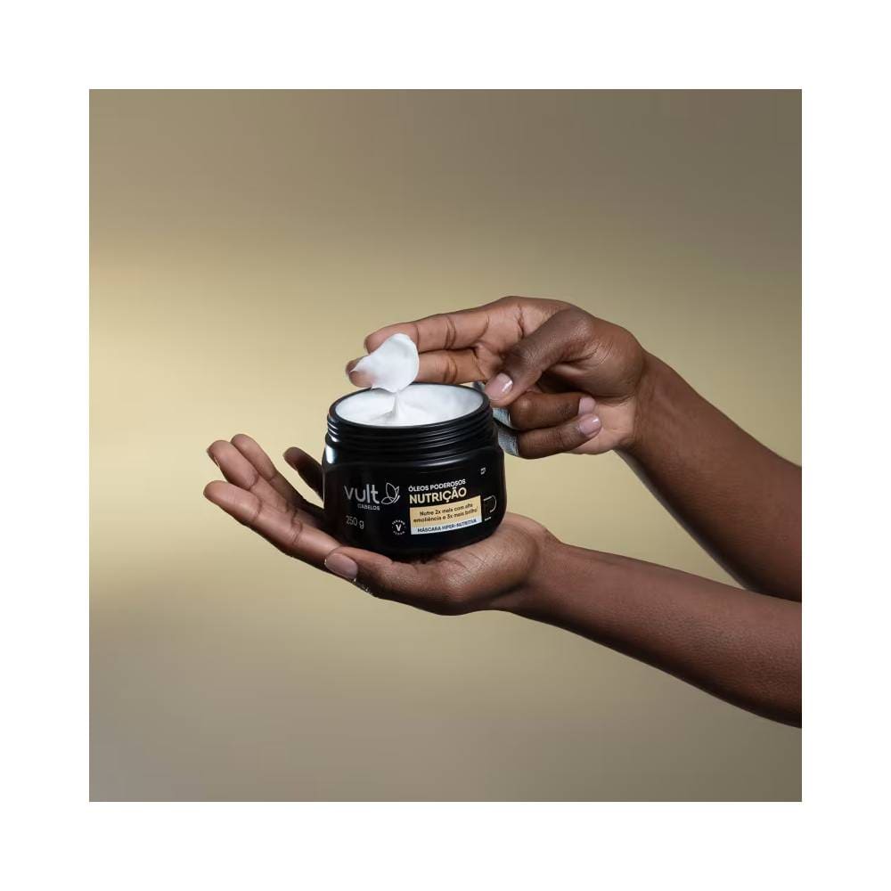 Mãos segurando pote aberto da Máscara Hiper-Nutritiva Vult mostrando textura cremosa