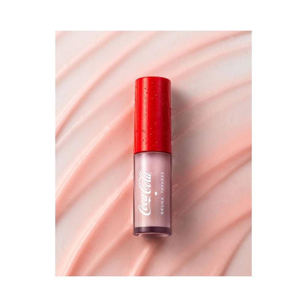 Lip Balm Bruna Tavares Coca-Cola com fundo rosa claro ondulado