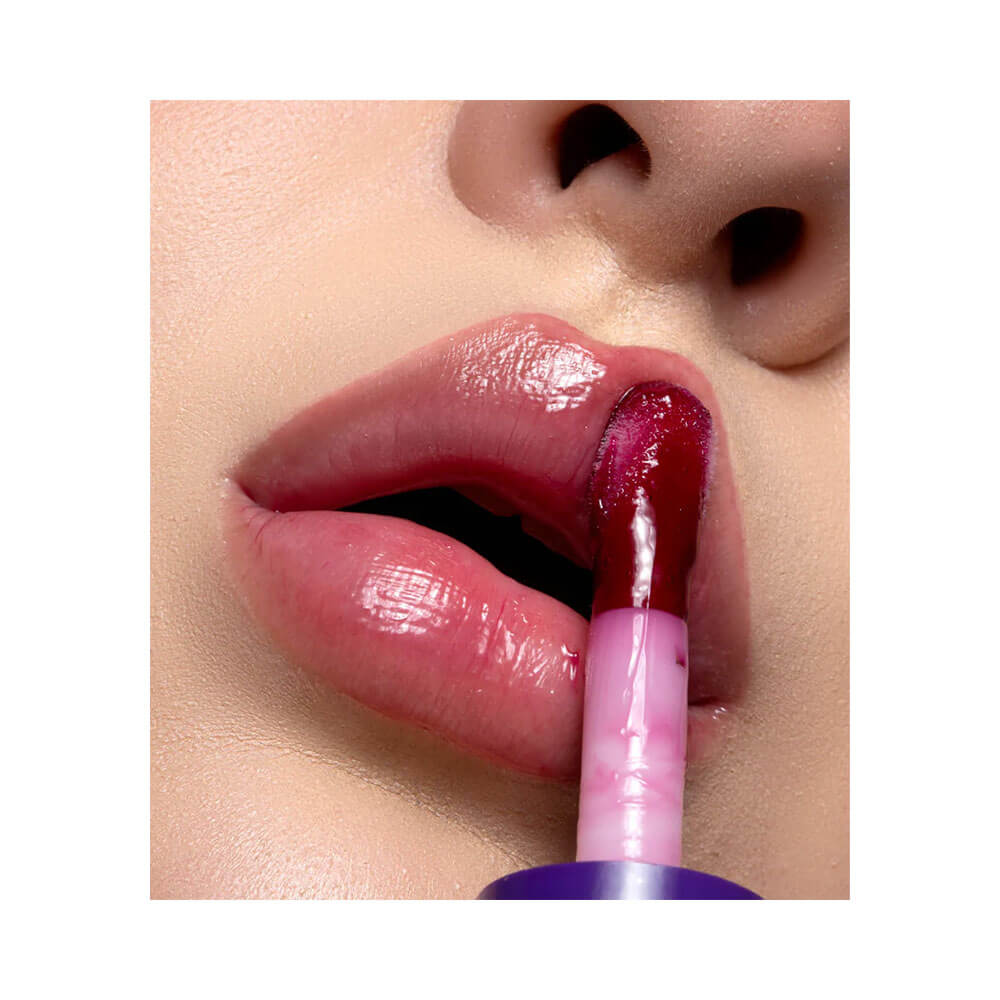 Lábios com brilho intenso e cor roxa do Lip Oil Dailus Uva aplicado