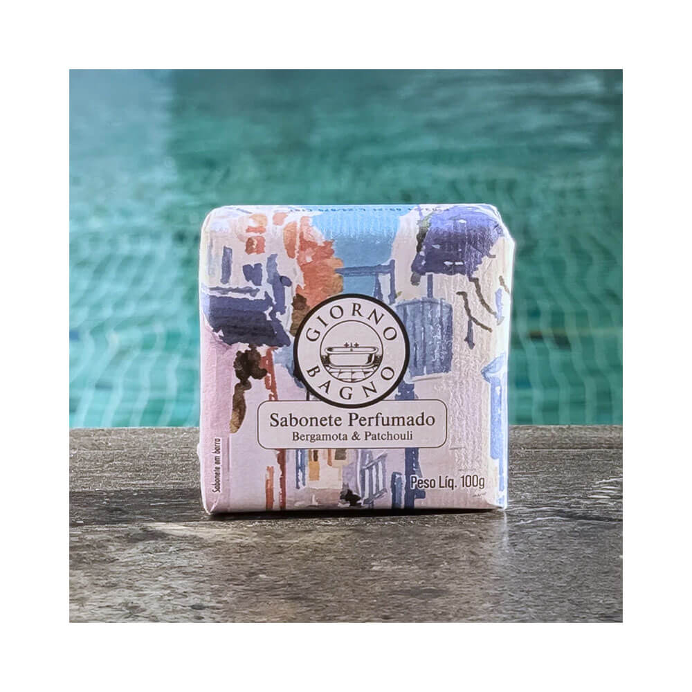 Sabonete Giorno Bagno Bergamota e Patchouli 100g embalado sobre superfície de madeira com fundo de piscina azul