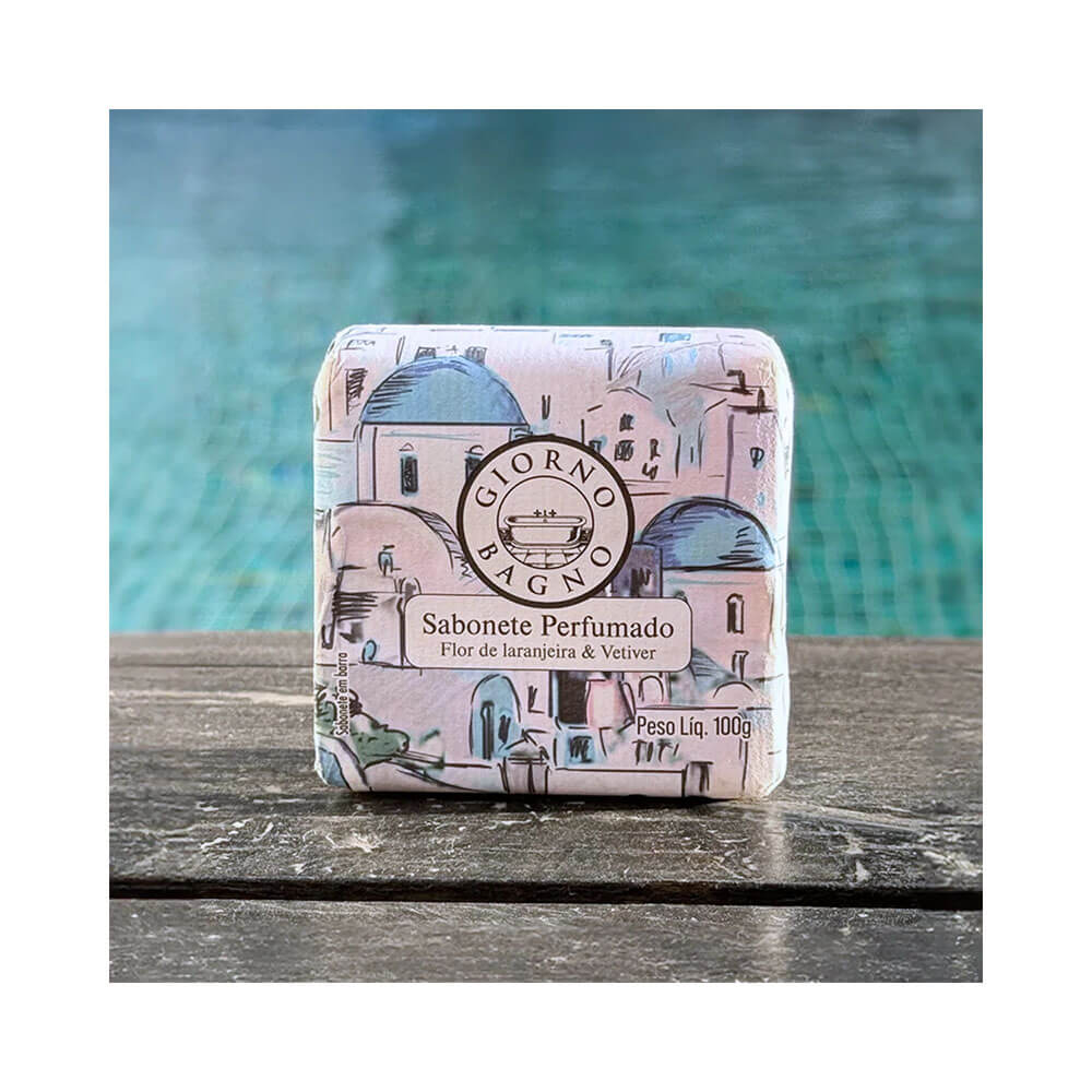 Sabonete Giorno Bagno Flor de Laranjeira e Vetiver 100g sobre superfície de madeira com fundo de piscina
