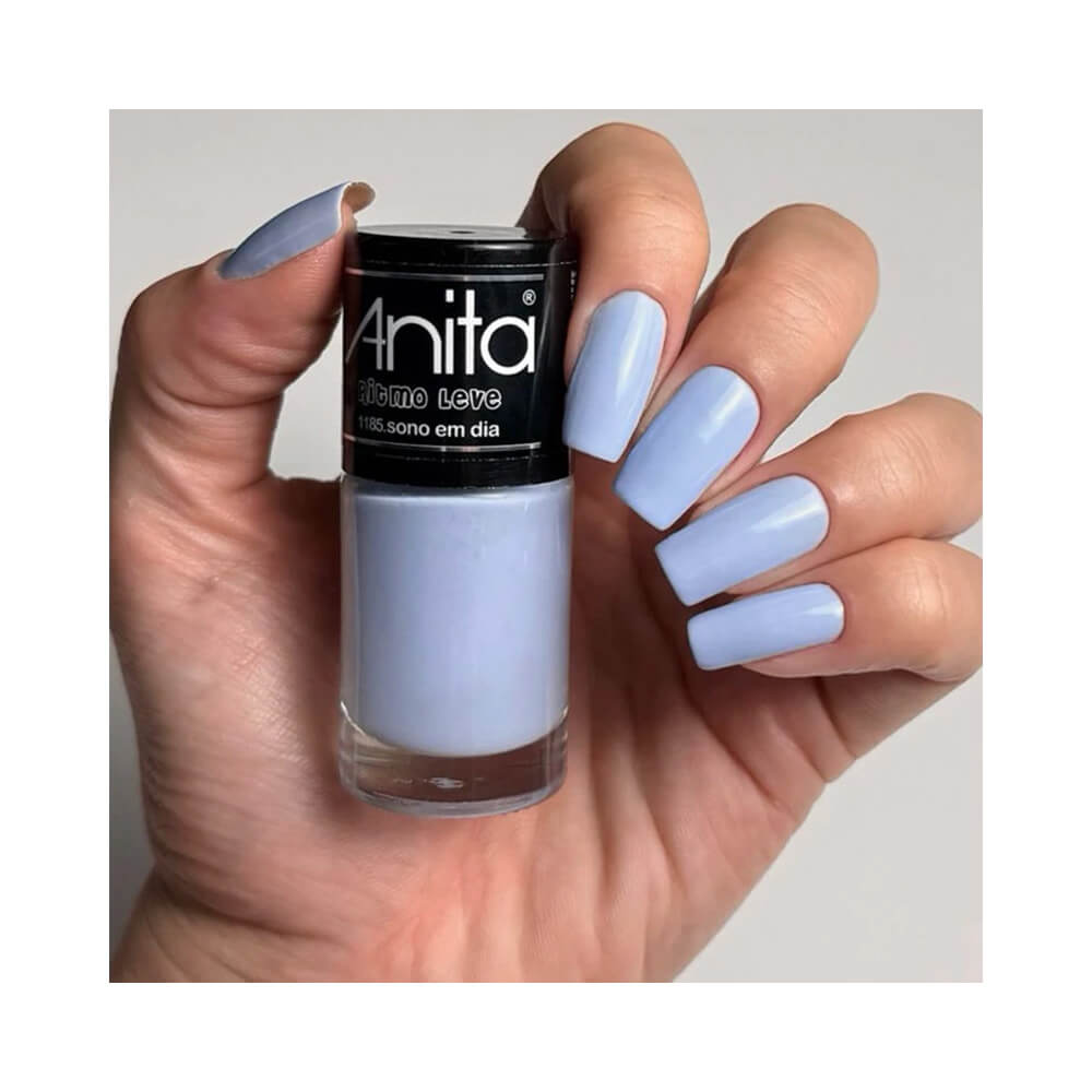 Mão feminina segurando esmalte Anita Ritmo Leve Sono em Dia, unhas pintadas com esmalte lilás claro
