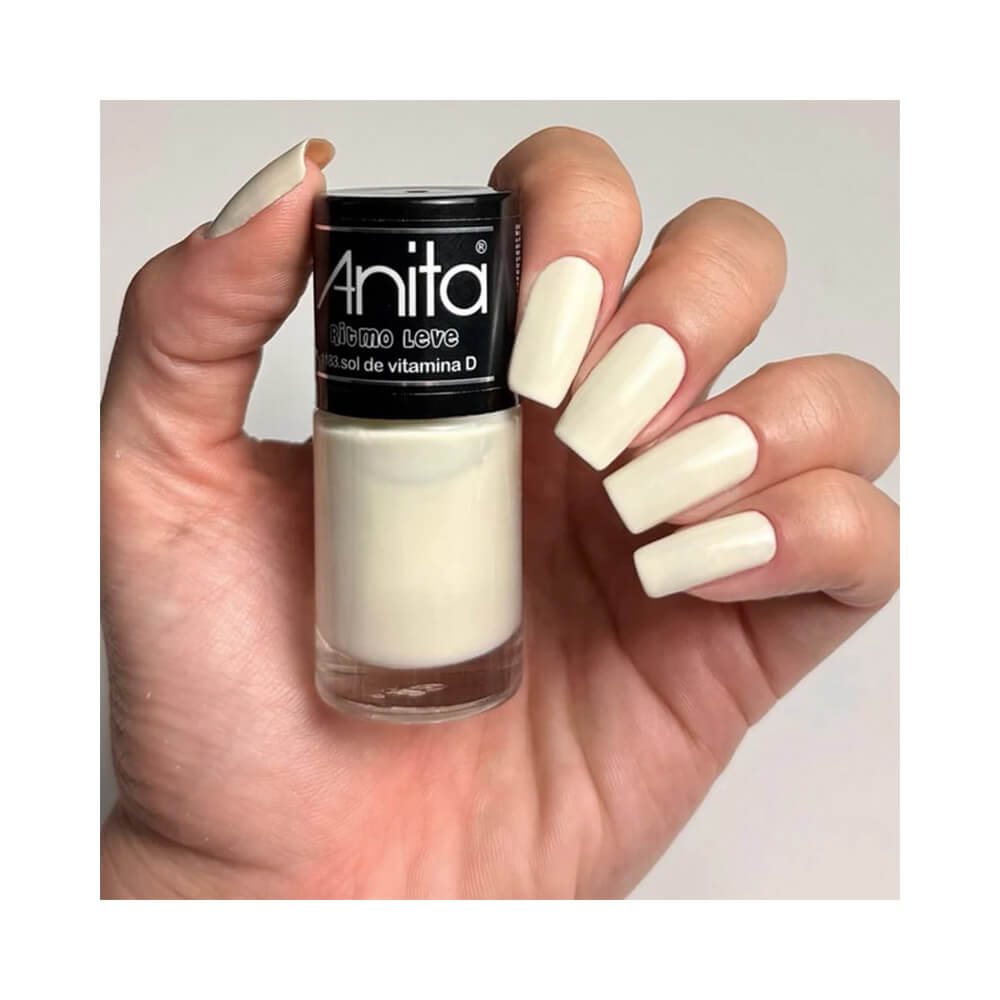 Mão segurando o esmalte Anita Ritmo Leve Sol de Vitamina D com unhas pintadas na mesma cor