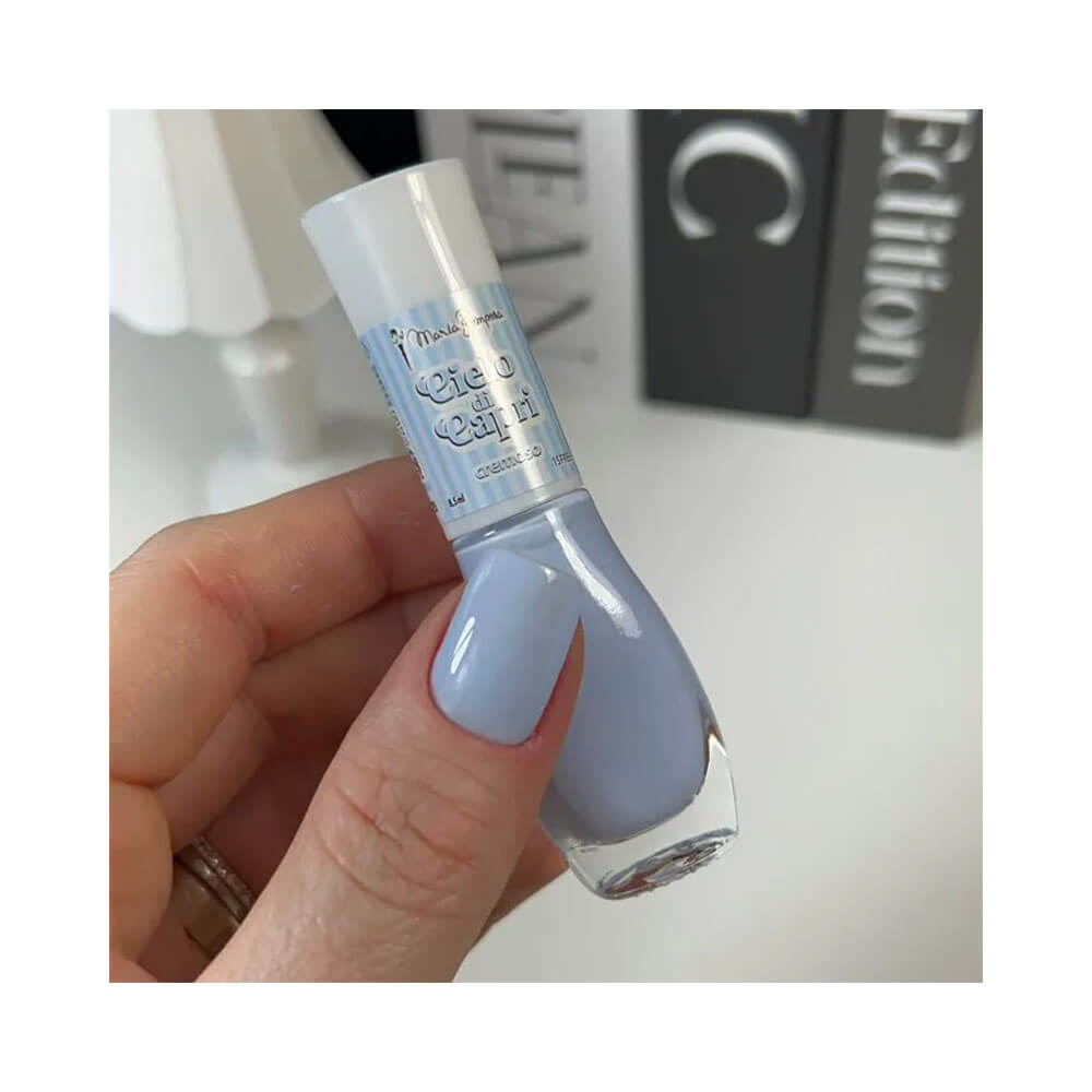 Mão feminina com unhas pintadas na cor Ciélo di Capri segurando o esmalte Maria Pomposa