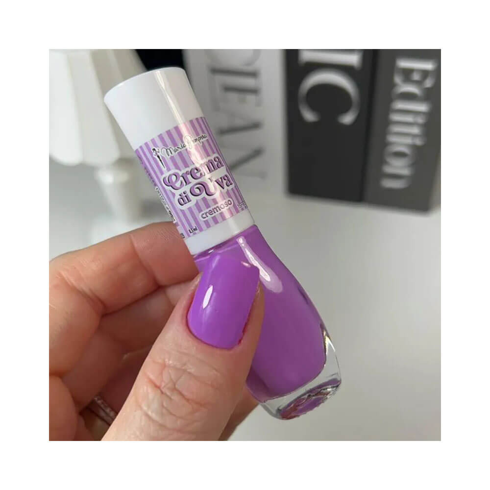Mão segurando esmalte Maria Pomposa La Dolce Vita Crema di Uva com cor aplicada nas unhas