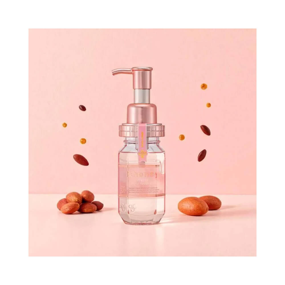 Frasco do óleo capilar sobre fundo rosa claro com elementos naturais ao redor