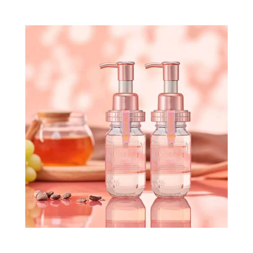 Dois frascos do óleo capilar lado a lado com ingredientes naturais ao fundo