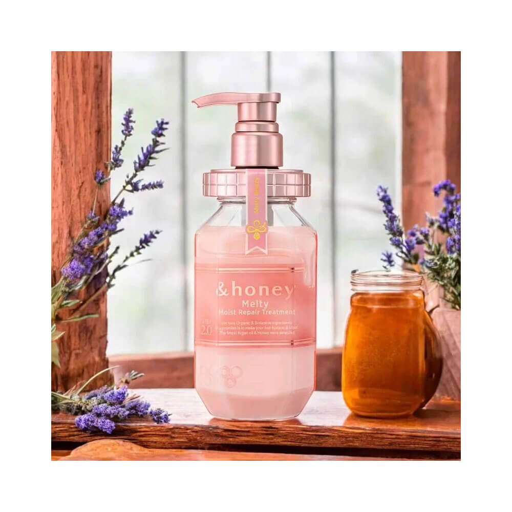Shampoo &Honey Melty Moist Repair 440ml ao lado de pote de mel e flores lilases