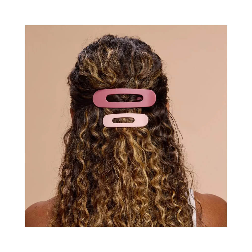 Mulher com cabelo cacheado usando presilhas Proart rosa e vinho