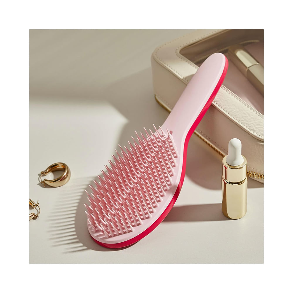 Escova Tangle Teezer The Ultimate Styler Pink sobre superfície clara ao lado de acessórios femininos